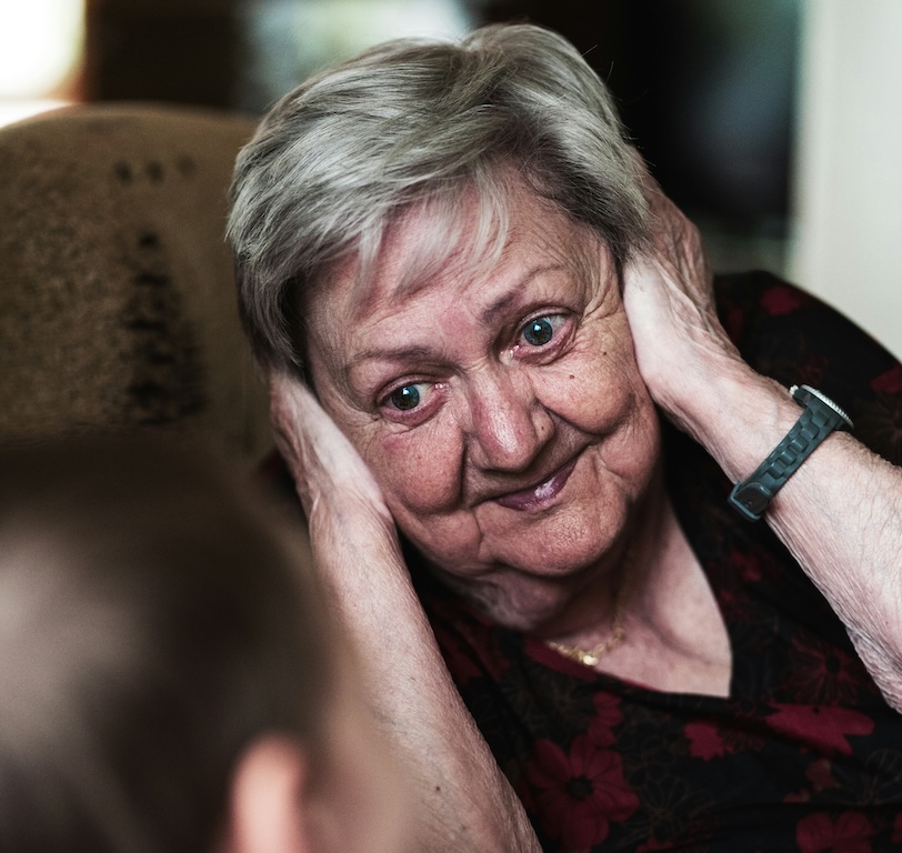 Dame de compagnie à domicile écoutant attentivement une personne âgée atteinte d'Alzheimer, illustrant l'accompagnement bienveillant.