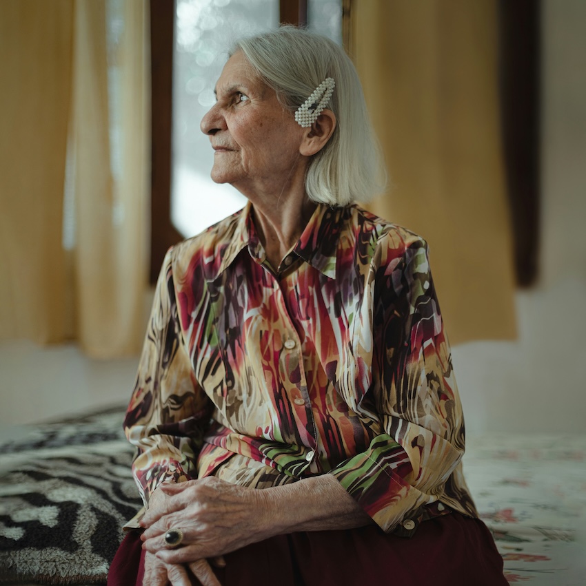 Portrait d'une femme âgée élégante assise dans sa chambre, illustrant le refus d'aide à domicile et la préservation de la dignité